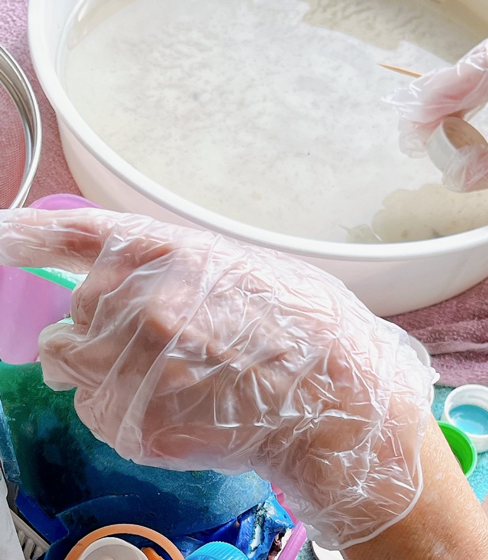 手袋をした手で、拾ったプラスチックを洗う作業